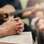 Christian prayer group with bible by playing the guitar to worship God