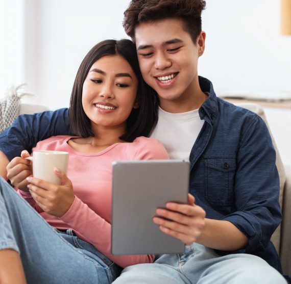 Asian Couple Using Tablet Computer Watching Movie Online At Home